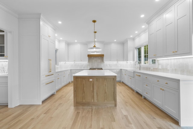 45 Robin Cir, Fairfield, CT 06824 - kitchen featuring a sink, light wood-style flooring, a kitchen island, backsplash, and crown molding