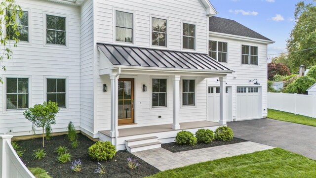 45 Robin Cir, Fairfield, CT 06824 - view of front of house with a standing seam roof, asphalt driveway, a porch, an attached garage, and metal roof