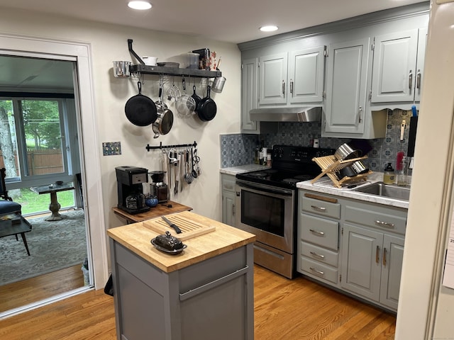 kitchen featuring gray cabinets, stainless steel electric range oven, wooden counters, ventilation hood, and light wood-type flooring