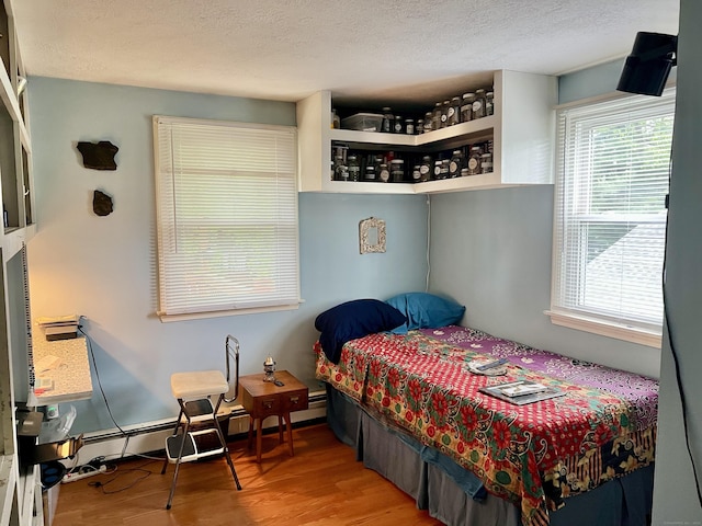 bedroom with multiple windows, wood finished floors, and a textured ceiling