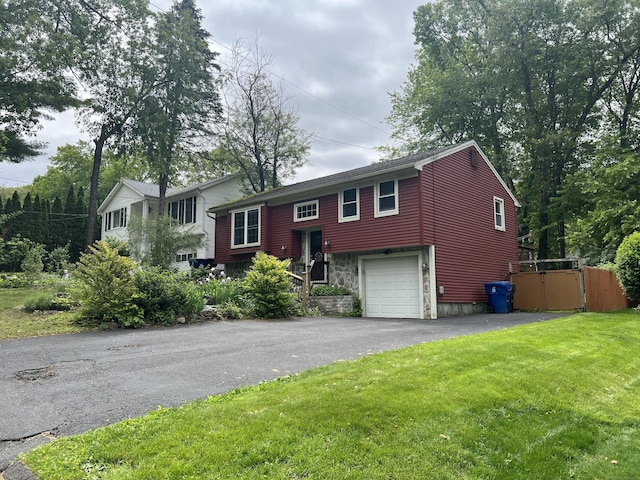 bi-level home with asphalt driveway, stone siding, and a garage
