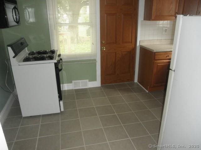 40 Wake St, Bridgeport, CT 06610 - kitchen with white appliances, light countertops, brown cabinets, tile patterned floors, and tasteful backsplash