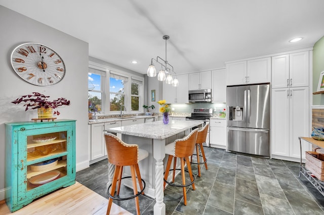 645 Prospect Ave Unit 11, West Hartford, CT 06105 - kitchen featuring appliances with stainless steel finishes, a sink, white cabinets, a kitchen island, and a kitchen breakfast bar