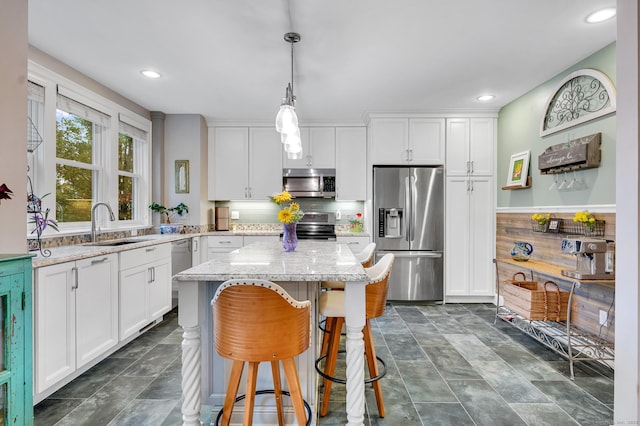 645 Prospect Ave Unit 11, West Hartford, CT 06105 - kitchen featuring stainless steel appliances, a sink, white cabinetry, a breakfast bar, and light stone countertops