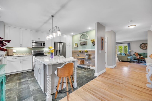 645 Prospect Ave Unit 11, West Hartford, CT 06105 - kitchen featuring appliances with stainless steel finishes, a breakfast bar area, white cabinets, a kitchen island, and recessed lighting
