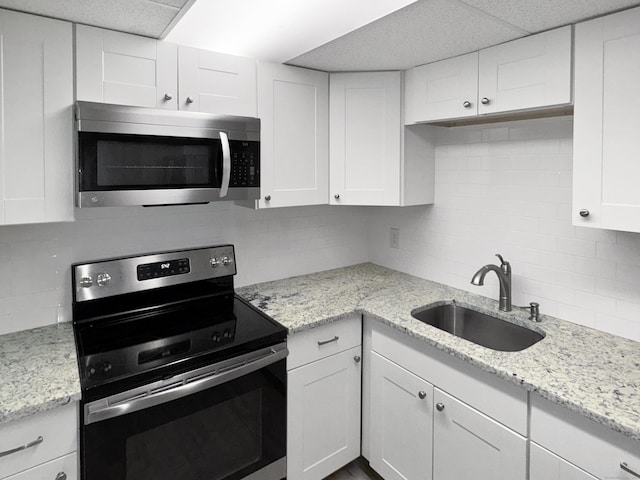 330 Short Beach Rd Apt F6, East Haven, CT 06512 - kitchen with appliances with stainless steel finishes, a sink, backsplash, white cabinetry, and light stone countertops