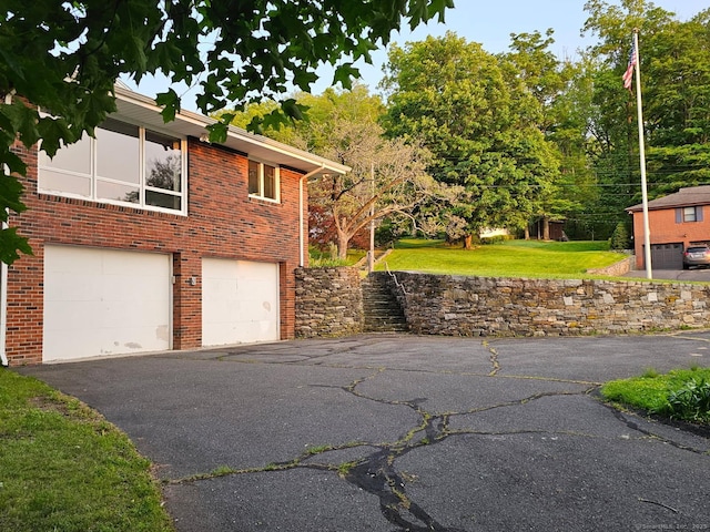 36 View St, Plainville, CT 06062 - view of home's exterior featuring asphalt driveway, an attached garage, brick siding, and a yard