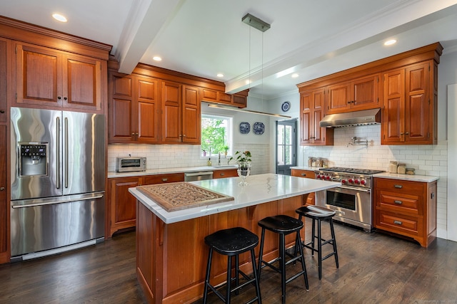 118 S St, Litchfield, CT 06759 - kitchen featuring appliances with stainless steel finishes, under cabinet range hood, dark wood finished floors, brown cabinets, and ornamental molding
