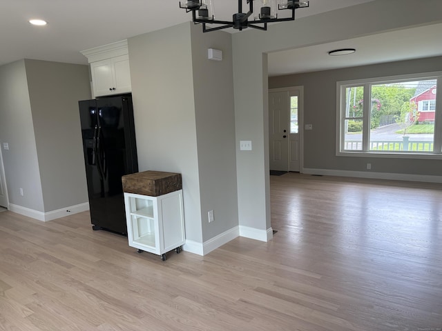 19 Race Ave, Plainville, CT 06062 - kitchen featuring black fridge with ice dispenser, a chandelier, white cabinetry, light wood-style flooring, and baseboards