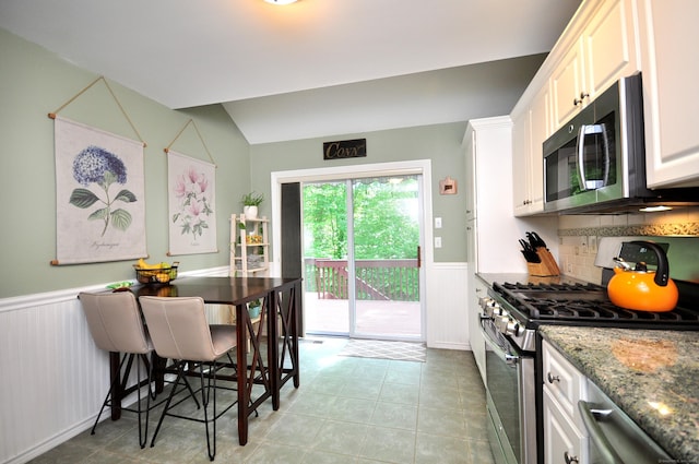 202 Castlewood Dr Unit 202, Bloomfield, CT 06002 - kitchen with stainless steel appliances, a wainscoted wall, stone counters, vaulted ceiling, and white cabinetry