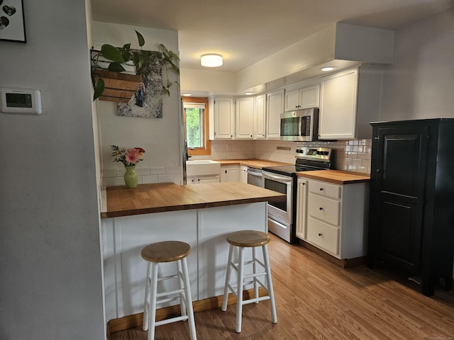 16 Walnut St (Pawcatuck), Unit Pawcatuck Stonington, CT 06379 - kitchen featuring wood counters, stainless steel appliances, white cabinetry, and tasteful backsplash