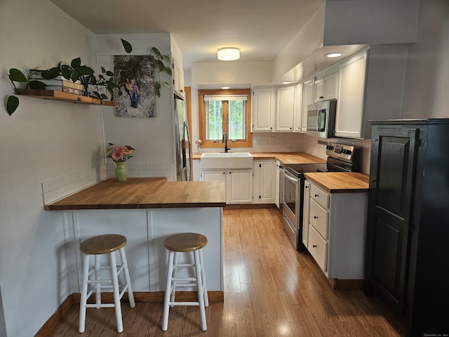 16 Walnut St (Pawcatuck), Unit Pawcatuck Stonington, CT 06379 - kitchen with butcher block counters, appliances with stainless steel finishes, a sink, a peninsula, and tasteful backsplash