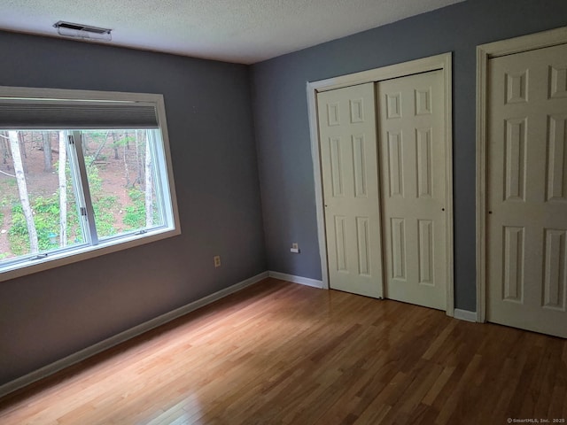 605 Whetstone Mls Unit 605, Killingly, CT 06241 - unfurnished bedroom featuring wood finished floors, baseboards, and a textured ceiling