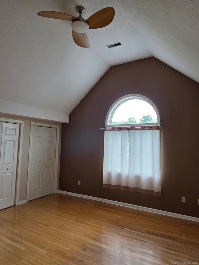605 Whetstone Mls Unit 605, Killingly, CT 06241 - unfurnished bedroom featuring light wood-style flooring, multiple closets, lofted ceiling, baseboards, and ceiling fan