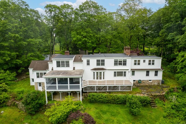 1208 Smith Ridge Rd, New Canaan, CT 06840 - back of property with a chimney, a sunroom, and a wooden deck