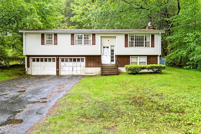 108 Gallivan Ln, Montville, CT 06382 - split foyer home featuring driveway, a chimney, a front lawn, a garage, and a wooded view