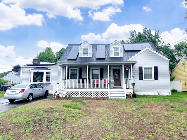 29 Hooker Rd, Bridgeport, CT 06610 - view of front facade with a porch, roof mounted solar panels, roof with shingles, and a front lawn