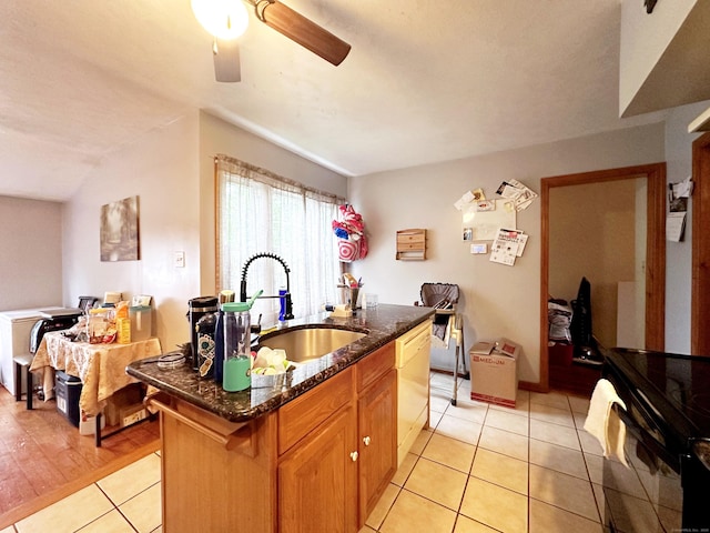 29 Hooker Rd, Bridgeport, CT 06610 - kitchen with light tile patterned floors, a center island with sink, dark stone countertops, a ceiling fan, and a sink