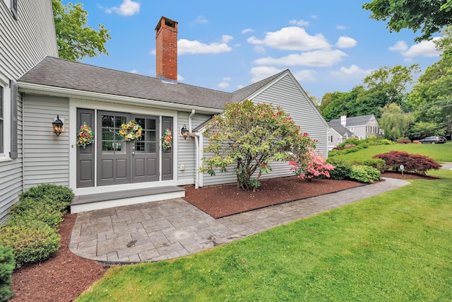 59 Ledyard Rd, West Hartford, CT 06117 - doorway to property with a chimney, a lawn, and a shingled roof