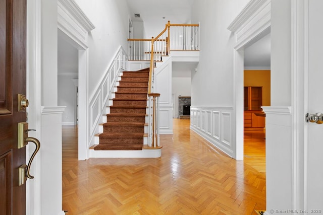 96 Norrans Ridge Dr, Ridgefield, CT 06877 - foyer entrance featuring stairs, a decorative wall, a wainscoted wall, a high ceiling, and crown molding