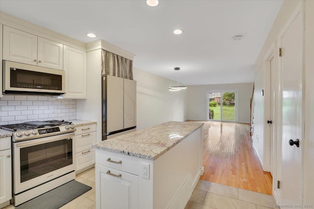165 Hampton Ct Unit 165, Newington, CT 06111 - kitchen with white appliances, light tile patterned floors, backsplash, a center island, and light stone counters