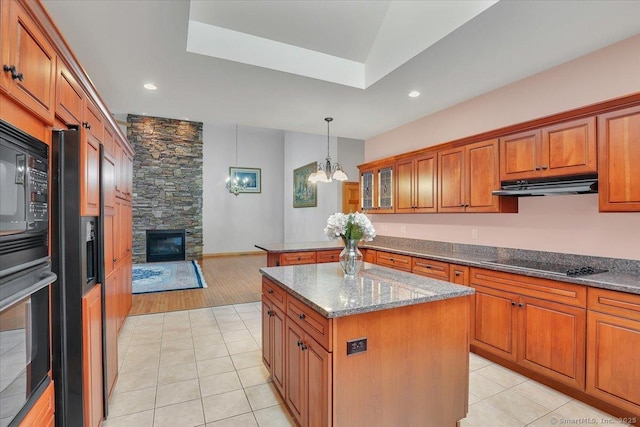 503 Dzen Way Unit 503, South Windsor, CT 06074 - kitchen with black appliances, under cabinet range hood, brown cabinets, a stone fireplace, and a chandelier