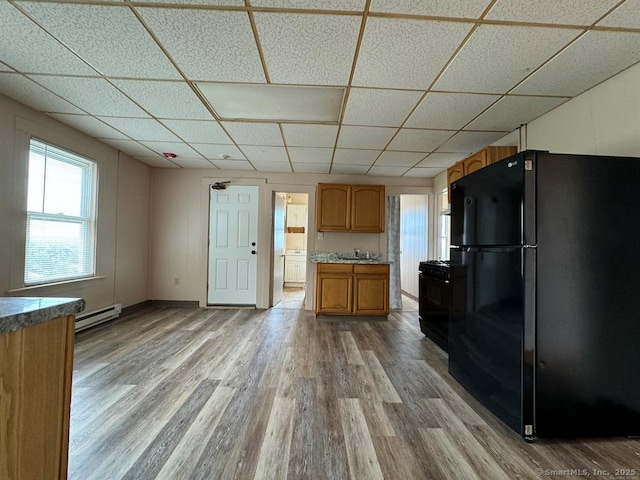 220 Kensington Ave, New Britain, CT 06051 - kitchen with freestanding refrigerator, a drop ceiling, light wood-style flooring, gas stove, and a baseboard heating unit