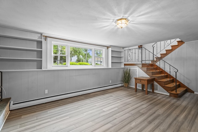 38 Rossie St, Stonington, CT 06355 - unfurnished living room featuring a baseboard heating unit, wood finished floors, stairway, and built in shelves