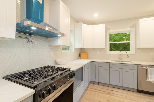 708 County Rd, Guilford, CT 06437 - kitchen featuring wall chimney range hood, black gas range oven, stainless steel dishwasher, decorative backsplash, and a sink