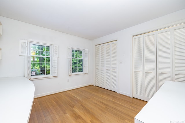 39 Chestnut Hill Rd, Simsbury, CT 06092 - unfurnished bedroom featuring two closets, light wood-style floors, and baseboards