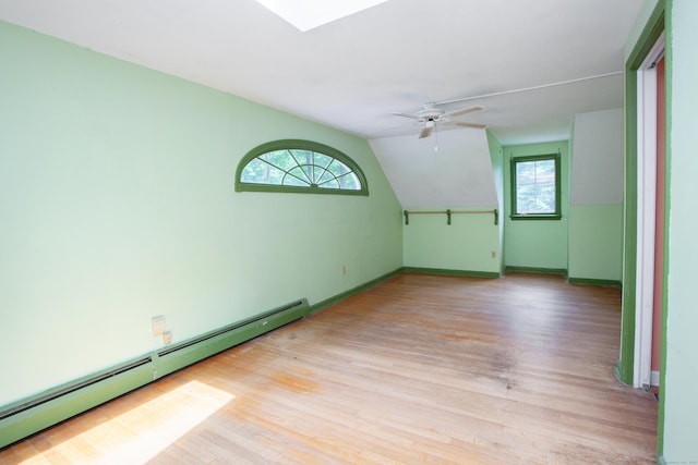 106 Hedgehog Ln, Simsbury, CT 06092 - empty room with a baseboard radiator, light wood-style floors, a skylight, ceiling fan, and vaulted ceiling