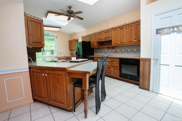 106 Hedgehog Ln, Simsbury, CT 06092 - kitchen featuring black appliances, ceiling fan, a skylight, brown cabinetry, and lofted ceiling