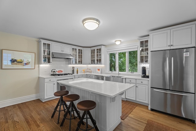 9 Rathbun Pl, Groton, CT 06355 - kitchen featuring stainless steel appliances, a sink, a kitchen bar, light countertops, and under cabinet range hood