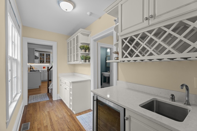 9 Rathbun Pl, Groton, CT 06355 - kitchen featuring beverage cooler, a sink, light wood-type flooring, white cabinetry, and open shelves