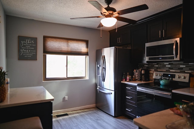 196 New Haven Ave Unit 217, Derby, CT 06418 - kitchen featuring appliances with stainless steel finishes, decorative backsplash, dark cabinetry, ceiling fan, and light countertops