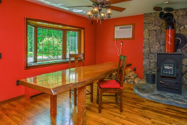 138 Baltic Hanover Rd, Sprague, CT 06330 - dining area featuring wood finished floors, ceiling fan, a wood stove, and a wall unit AC