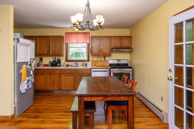 138 Baltic Hanover Rd, Sprague, CT 06330 - kitchen featuring a baseboard radiator, appliances with stainless steel finishes, under cabinet range hood, a chandelier, and brown cabinets