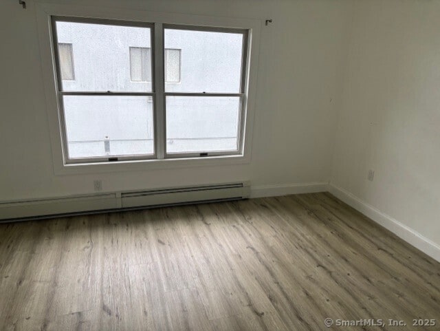 61 Clinton Ave Apt 6, Stamford, CT 06901 - spare room with a baseboard heating unit, wood finished floors, baseboards, and healthy amount of natural light