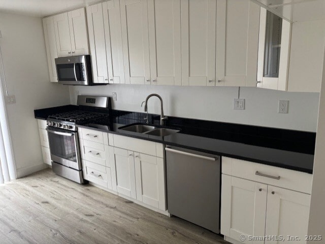 61 Clinton Ave Apt 6, Stamford, CT 06901 - kitchen featuring appliances with stainless steel finishes, a sink, dark countertops, and light wood finished floors