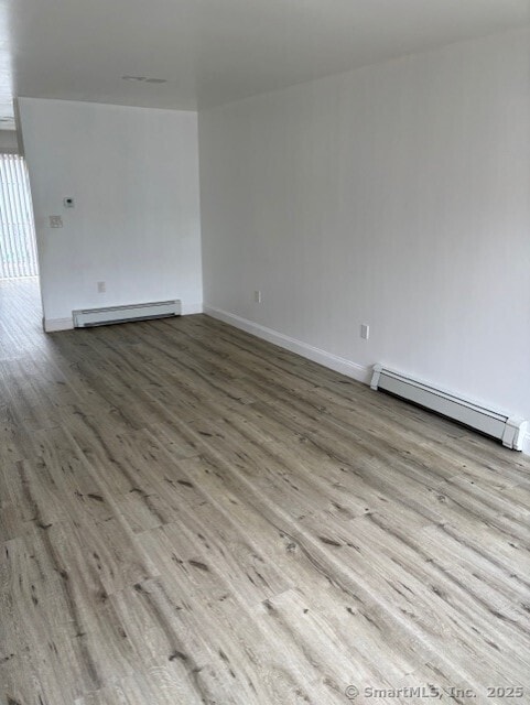 61 Clinton Ave Apt 6, Stamford, CT 06901 - spare room featuring a baseboard radiator, wood finished floors, and baseboards