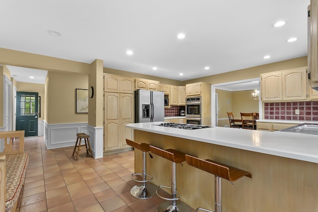 440 Hilltop Rd, Bridgeport, CT 06605 - kitchen featuring appliances with stainless steel finishes, a peninsula, a kitchen bar, tasteful backsplash, and a wainscoted wall