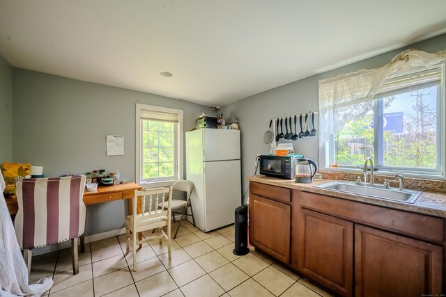 88 Boston Post Rd, Milford, CT 06460 - kitchen featuring freestanding refrigerator, a sink, black microwave, light tile patterned flooring, and brown cabinets