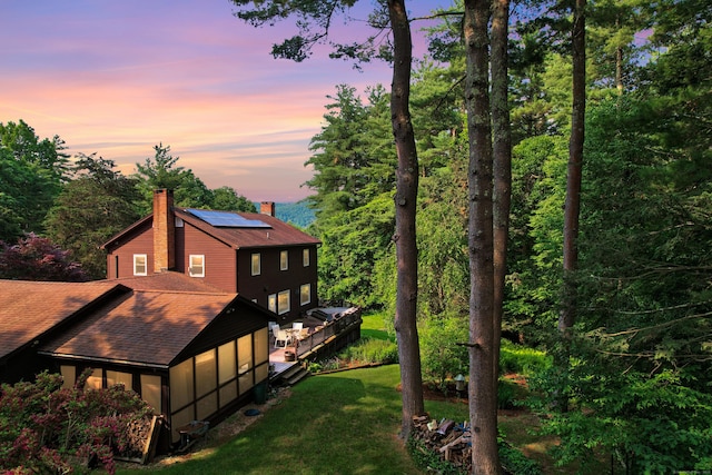 11 College Hill Rd, North Canaan, CT 06018 - back of property at dusk with a chimney, roof mounted solar panels, a yard, and a shingled roof