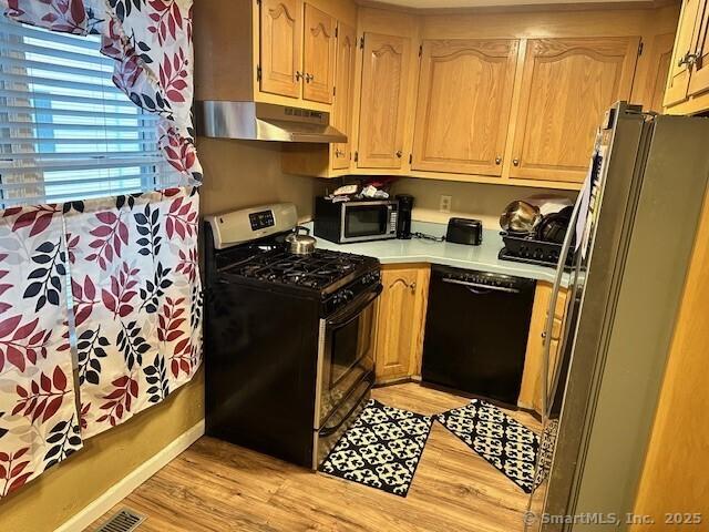 243 Lawlor St Apt 2C, New Britain, CT 06051 - kitchen with stainless steel appliances, under cabinet range hood, light wood-type flooring, and light countertops
