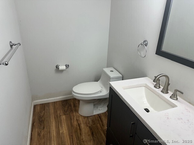 243 Lawlor St Apt 2C, New Britain, CT 06051 - bathroom featuring vanity, toilet, wood finished floors, and baseboards