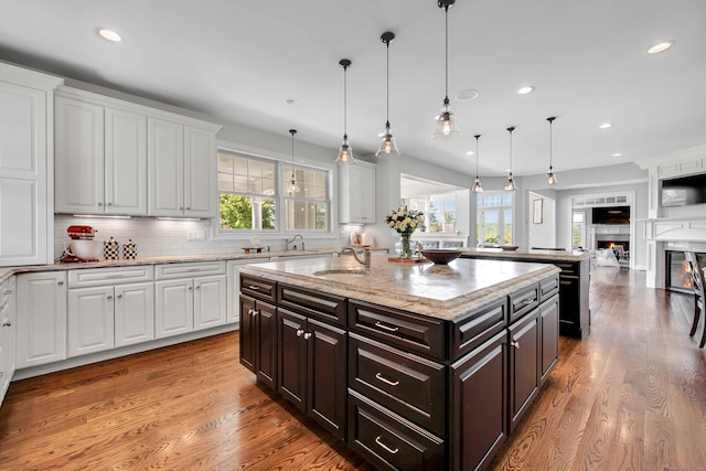 562 Upper Grassy Hill Rd, Woodbury, CT 06798 - kitchen with white cabinetry, recessed lighting, a warm lit fireplace, an island with sink, and tasteful backsplash