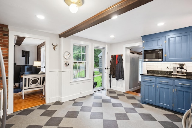 291 Hopmeadow St, Simsbury, CT 06089 - kitchen featuring stainless steel microwave, blue cabinets, light floors, dark countertops, and a wood stove