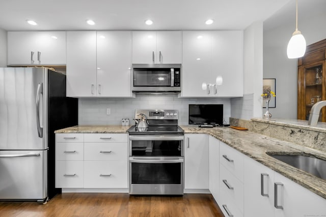 26 Legend Hill Rd Unit 26, Madison, CT 06443 - kitchen featuring appliances with stainless steel finishes, a sink, white cabinets, tasteful backsplash, and light stone counters