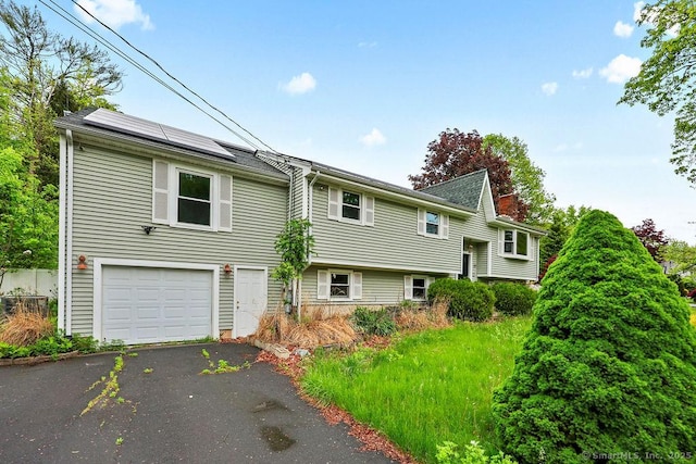 99 Redwood Dr, Bristol, CT 06010 - view of front of property with roof mounted solar panels, a garage, and driveway