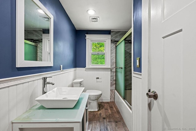 99 Redwood Dr, Bristol, CT 06010 - bathroom featuring toilet, wainscoting, hardwood / wood-style floors, vanity, and enclosed tub / shower combo